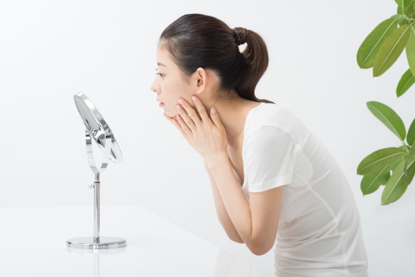 鏡でニキビを気にする女性